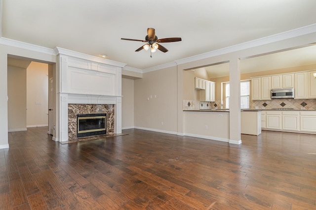 unfurnished living room featuring a high end fireplace, ornamental molding, and dark wood-type flooring