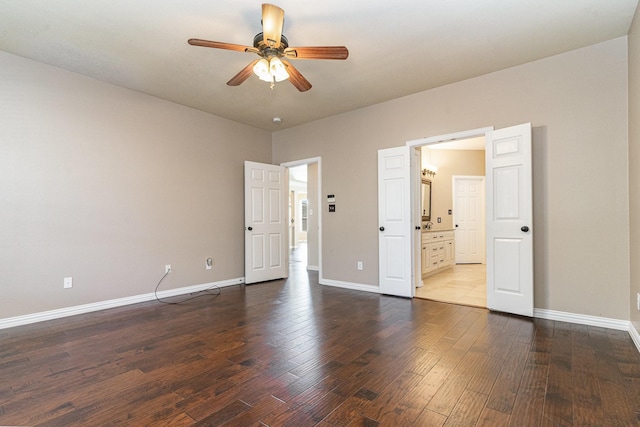 unfurnished bedroom with ensuite bath, ceiling fan, and dark wood-type flooring