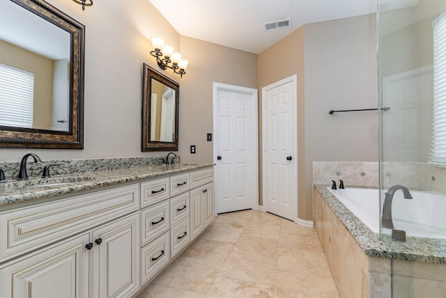 bathroom with tile patterned floors, vanity, and a relaxing tiled tub