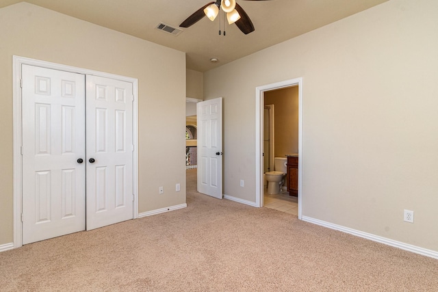 unfurnished bedroom featuring ceiling fan, light colored carpet, ensuite bath, and a closet