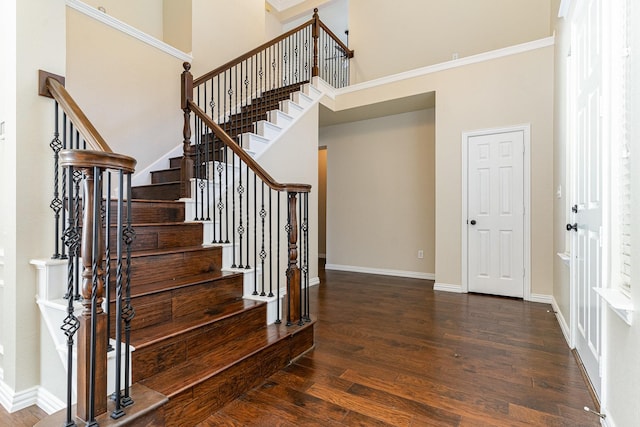 stairway with wood-type flooring and a high ceiling