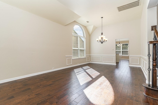 empty room with lofted ceiling, dark hardwood / wood-style floors, and a chandelier