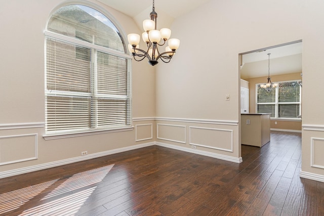 empty room with dark hardwood / wood-style flooring, lofted ceiling, and a chandelier