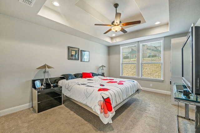 bedroom featuring light carpet, a raised ceiling, and ceiling fan