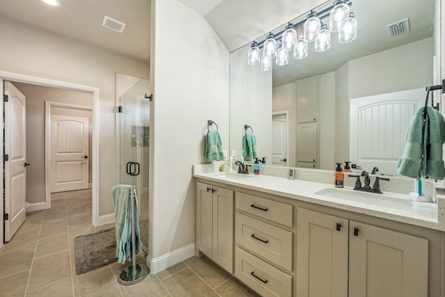 bathroom with a shower with door, vanity, and tile patterned floors