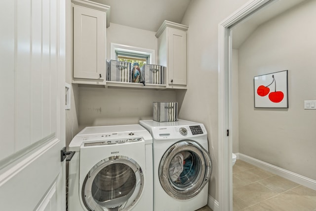 clothes washing area with light tile patterned floors, washing machine and dryer, and cabinets