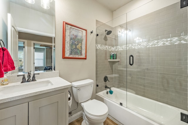 full bathroom featuring enclosed tub / shower combo, vanity, and toilet