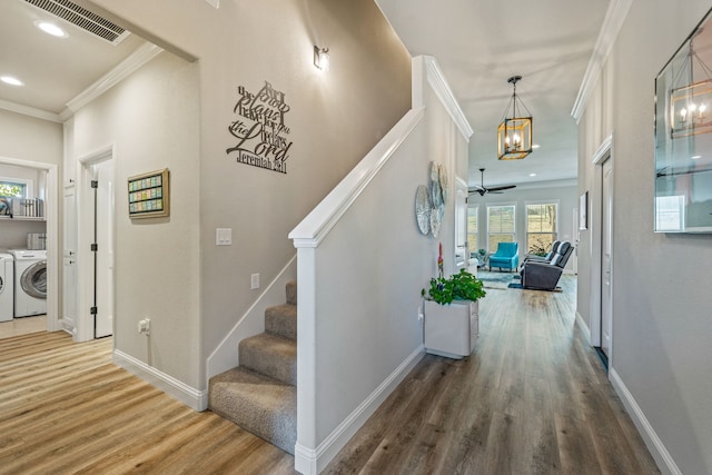 interior space with ornamental molding, washer and clothes dryer, and hardwood / wood-style floors