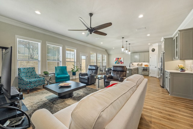 living room with ornamental molding, light hardwood / wood-style floors, and ceiling fan