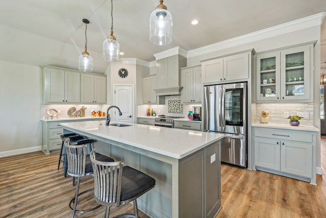 kitchen with pendant lighting, sink, a breakfast bar area, premium range hood, and appliances with stainless steel finishes