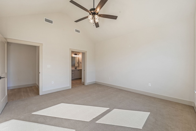 unfurnished bedroom with ensuite bathroom, light colored carpet, ceiling fan, and high vaulted ceiling