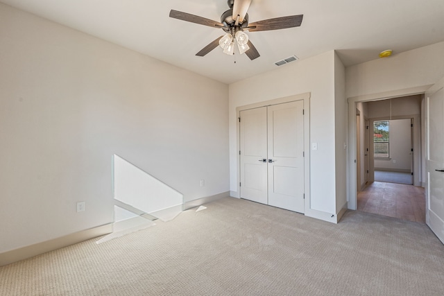 unfurnished bedroom featuring light carpet, a closet, and ceiling fan