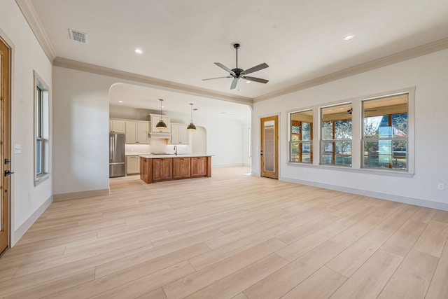 unfurnished living room featuring sink, crown molding, light hardwood / wood-style flooring, and ceiling fan