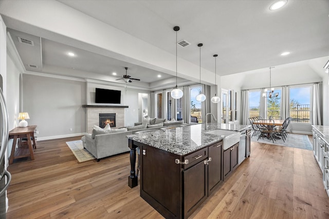 kitchen with light stone countertops, dark brown cabinetry, hardwood / wood-style flooring, and sink