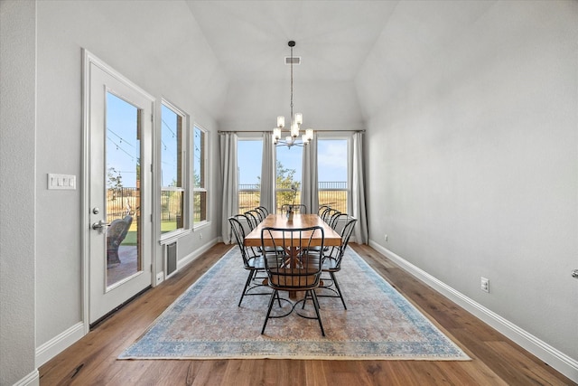 dining room featuring wood-type flooring, vaulted ceiling, and an inviting chandelier