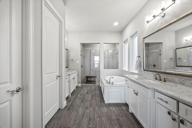 bathroom with hardwood / wood-style floors, vanity, and shower with separate bathtub