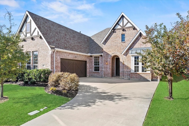 tudor-style house featuring a front yard and a garage