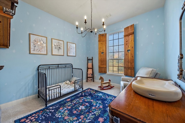 bedroom featuring carpet floors, a crib, and a notable chandelier