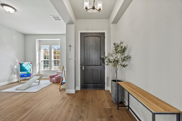 foyer entrance featuring wood-type flooring and an inviting chandelier