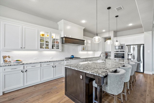 kitchen featuring a kitchen island with sink, light hardwood / wood-style flooring, white cabinets, and stainless steel appliances