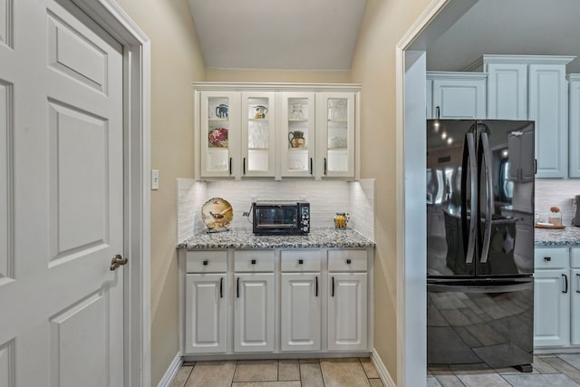 kitchen with black refrigerator, decorative backsplash, and white cabinets