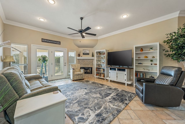 living room featuring a tile fireplace, light tile patterned floors, ceiling fan, and crown molding