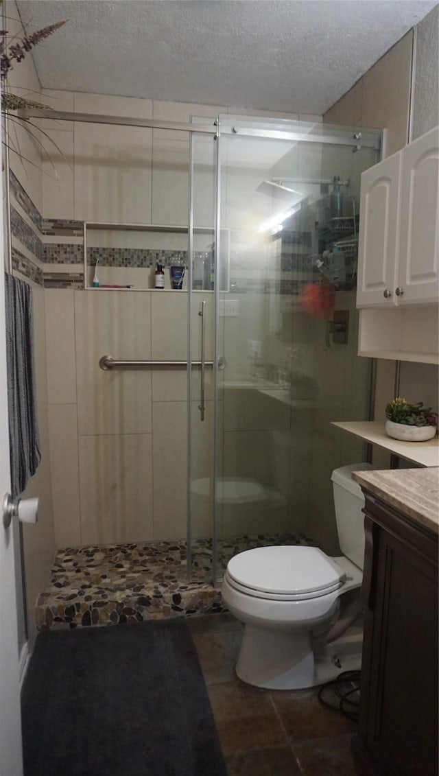 bathroom with tile patterned flooring, a textured ceiling, toilet, vanity, and a shower with shower door