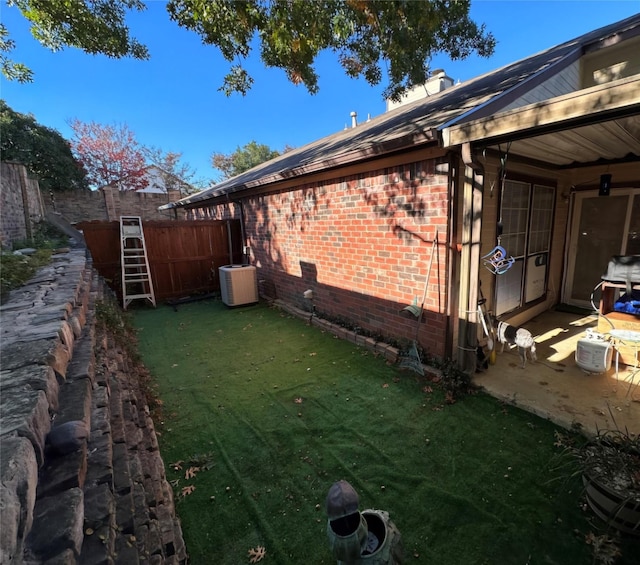 view of side of home with central AC unit and a yard