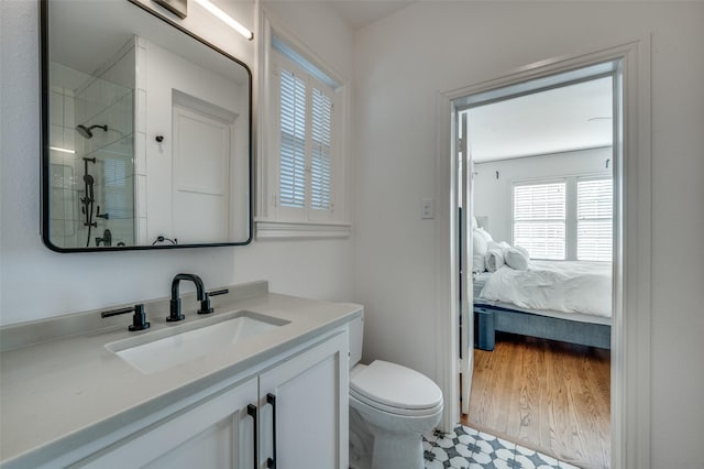 bathroom with hardwood / wood-style floors, vanity, toilet, and a tile shower