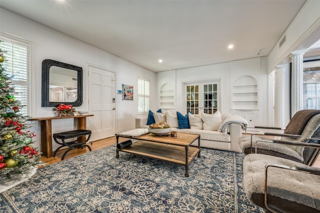 living room with decorative columns, hardwood / wood-style floors, built in features, and french doors