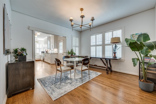 dining room with a notable chandelier, sink, and light hardwood / wood-style flooring