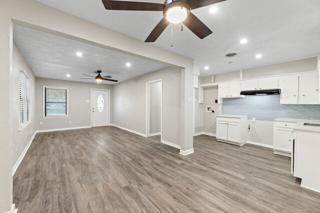 kitchen featuring backsplash, sink, ceiling fan, light wood-type flooring, and white cabinetry