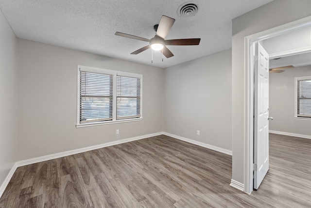 spare room featuring ceiling fan, light wood-type flooring, and a textured ceiling