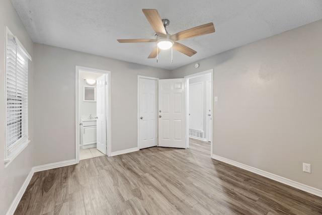 unfurnished bedroom with ensuite bathroom, light hardwood / wood-style flooring, ceiling fan, and a textured ceiling