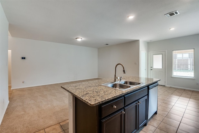 kitchen featuring light carpet, light stone countertops, sink, dishwasher, and an island with sink