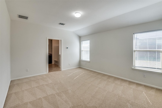 carpeted spare room with vaulted ceiling