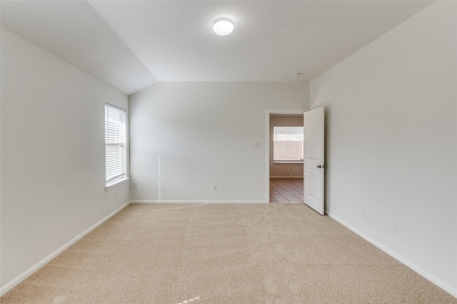 unfurnished room featuring plenty of natural light, light carpet, and vaulted ceiling