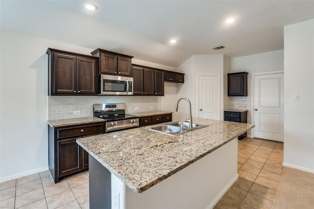 kitchen with decorative backsplash, appliances with stainless steel finishes, a kitchen island with sink, and sink