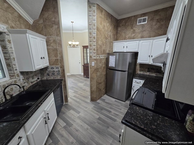 kitchen with stainless steel refrigerator, white cabinetry, sink, light hardwood / wood-style flooring, and tile walls