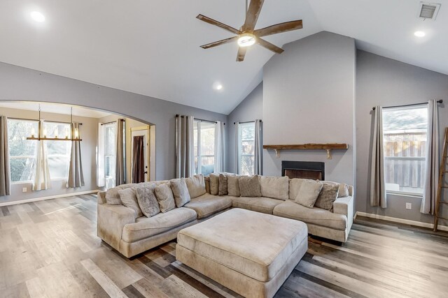 living room with ceiling fan with notable chandelier, high vaulted ceiling, and hardwood / wood-style floors