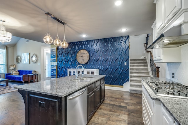 kitchen with a sink, appliances with stainless steel finishes, dark wood finished floors, and an accent wall