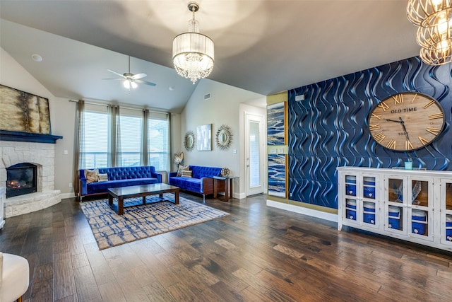 living area featuring wood finished floors, baseboards, a stone fireplace, vaulted ceiling, and an accent wall