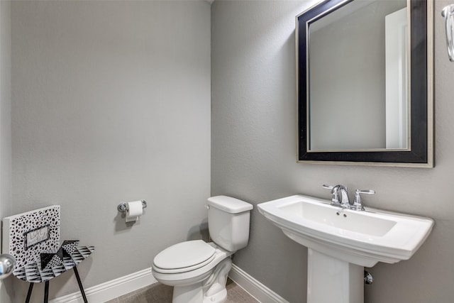 bathroom with toilet, baseboards, and a sink