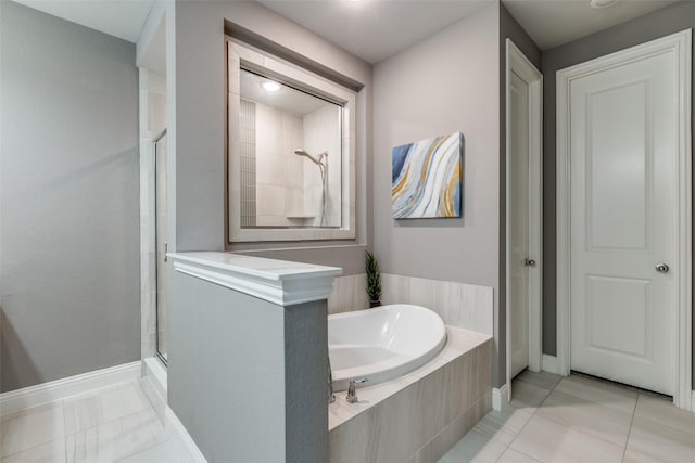 bathroom with baseboards, a bath, a shower stall, and tile patterned flooring