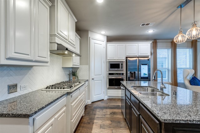 kitchen with a sink, appliances with stainless steel finishes, dark wood-style flooring, and white cabinetry