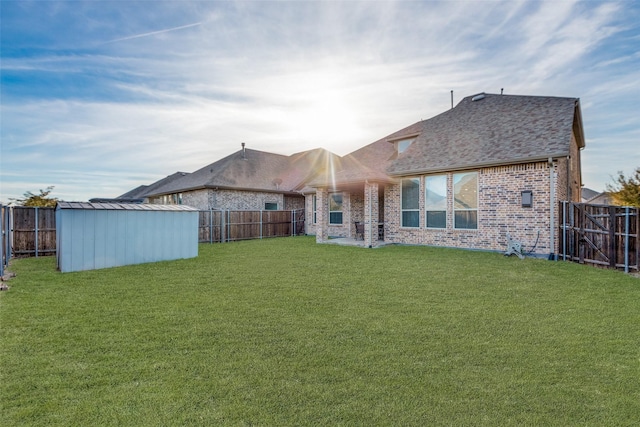 back of house featuring a yard, brick siding, and a fenced backyard