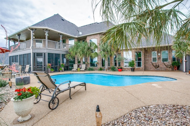 view of swimming pool with a sunroom, a diving board, and a patio area