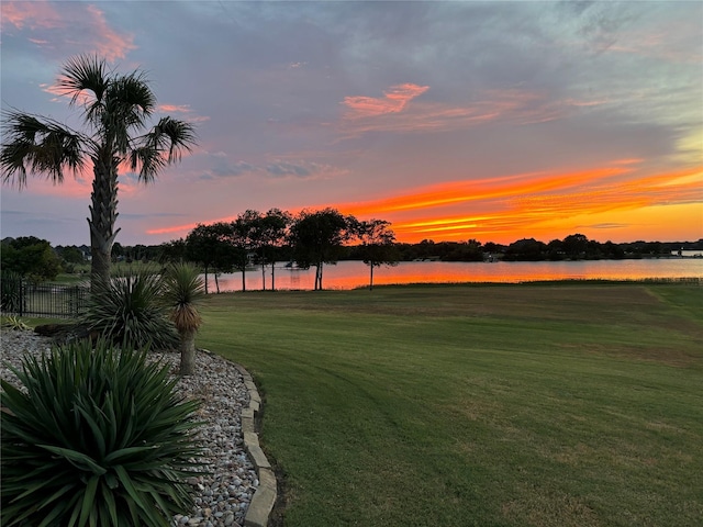 yard at dusk featuring a water view