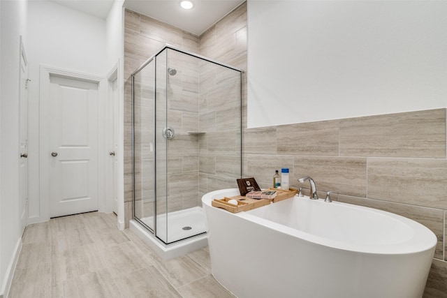 bathroom with hardwood / wood-style flooring, tile walls, and shower with separate bathtub