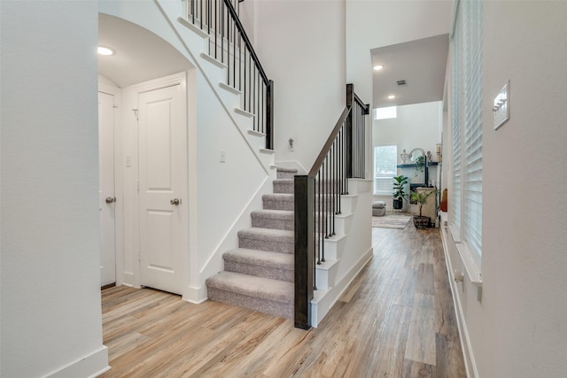 staircase with hardwood / wood-style flooring and a high ceiling